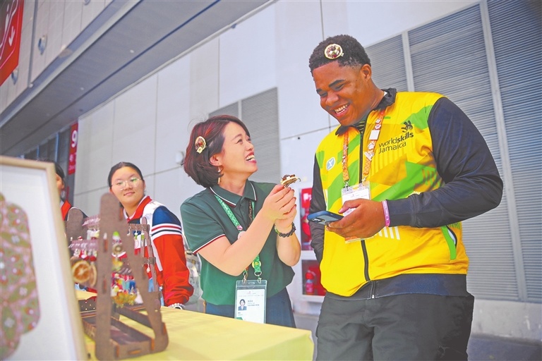 9月23日,来自牙买加的参赛选手在世界技能博览会河南医药健康技师学院展台前体验中药饰品。
