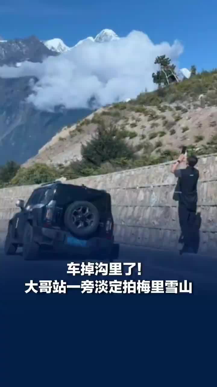 车开进沟里大哥站一旁淡定拍雪山