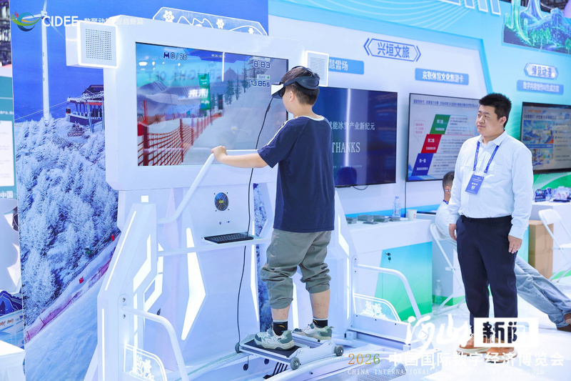 图为参观数博会的小观众佩戴VR头显体验模拟滑雪机。