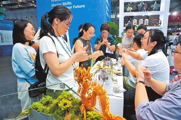 9月24日,观众在世界技能博览会郑州商业技师学院展台前了解铜丝编织技艺。