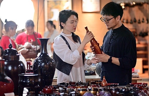 市级非遗代表性传承人陈武森(右)向游客介绍庐陵螺钿大漆作品。