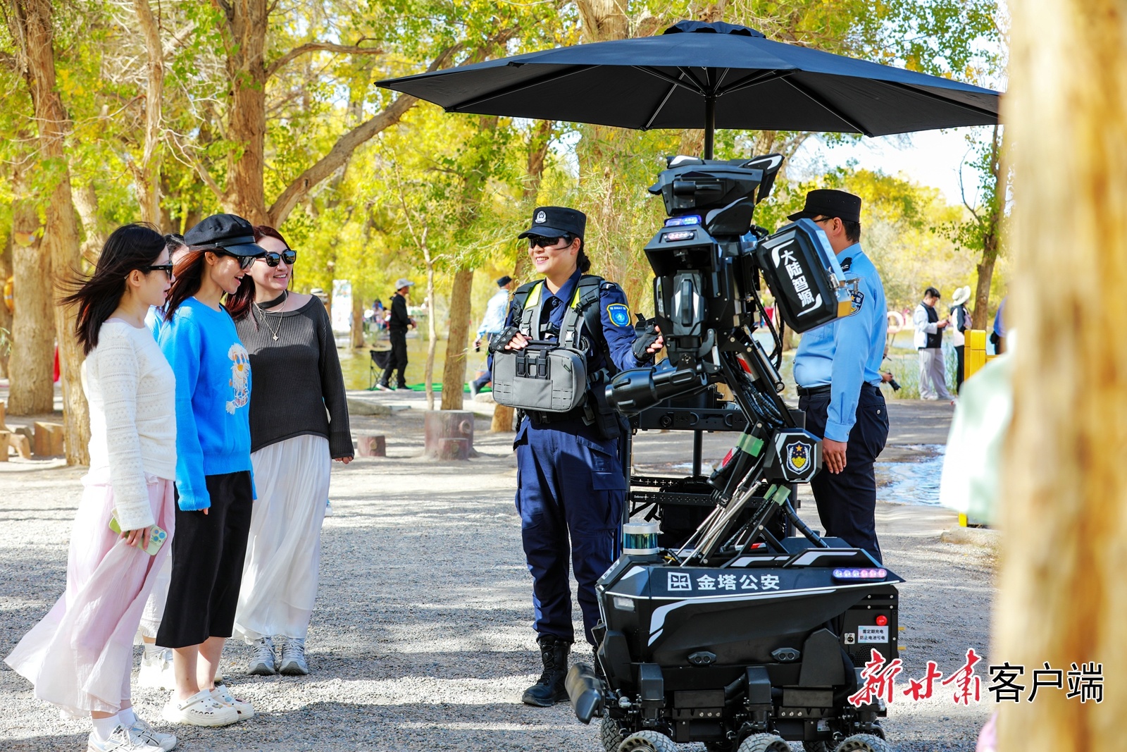 警用机器人在金塔沙漠胡杨林景区巡逻，吸引游客驻足观看、互动。新甘肃&middot;甘肃日报通讯员　曹红祖　摄