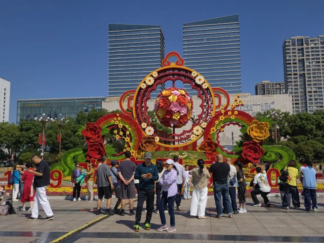 市民游客在南昌八一广场大花坛前拍照打卡。