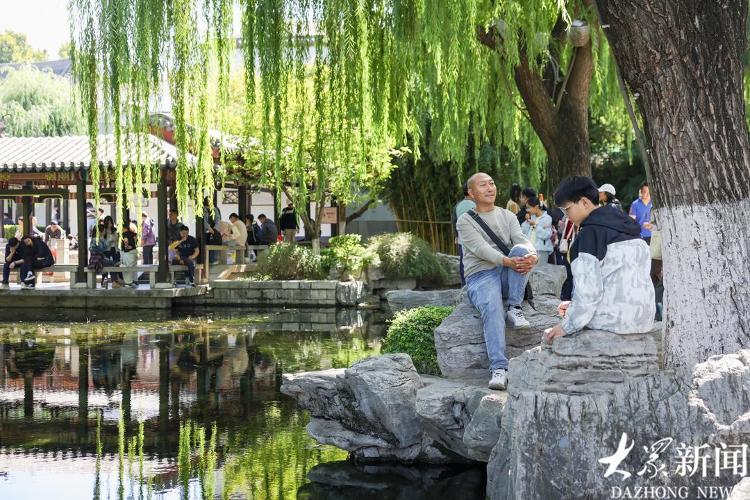 10月4日下午,济南五龙潭公园游人络绎不绝,不少游客在池边观赏游鱼。