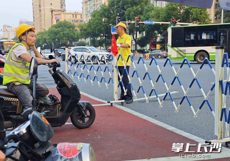 晚报大道车站北路口红灯亮起,伸缩护栏展开,将非机动车拦在等候区内。