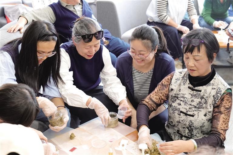 省图书馆举办的读书会活动上,老人们共同制作艾草香牌。张婧 摄