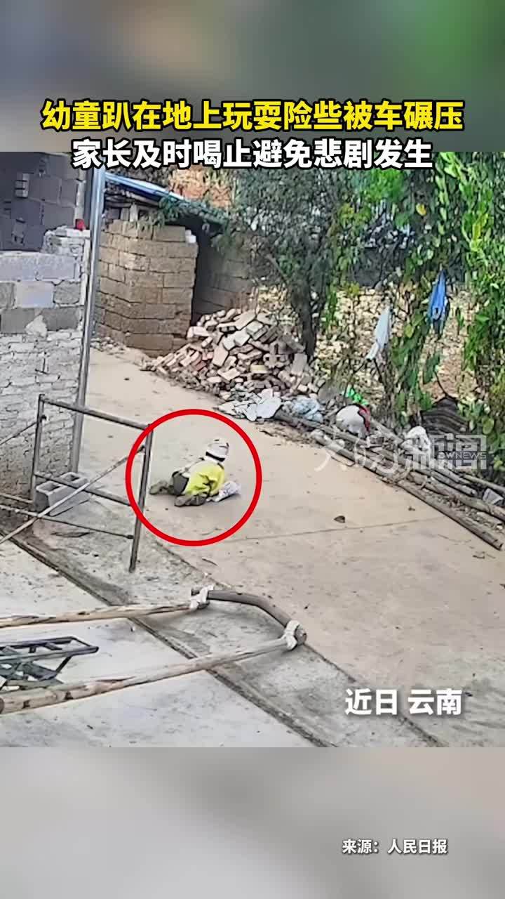 幼童趴在地上玩耍险些被车碾压 家长及时喝止避免悲剧发生