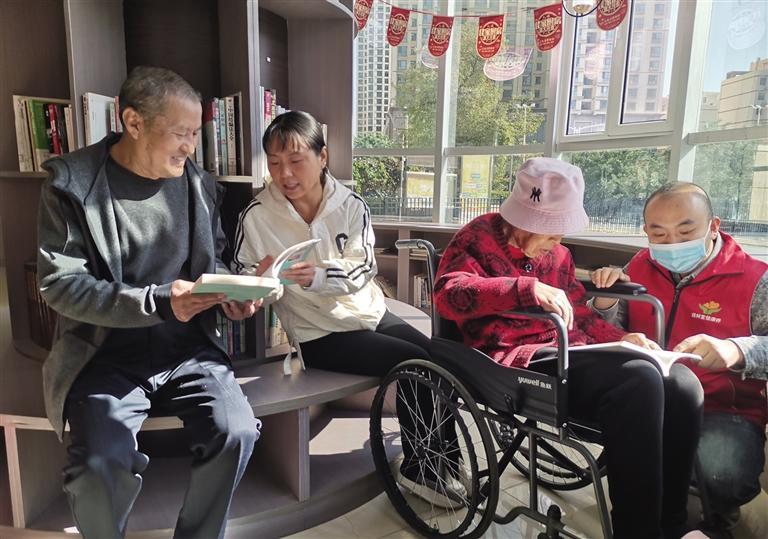 护工陪伴老人在读书角阅读