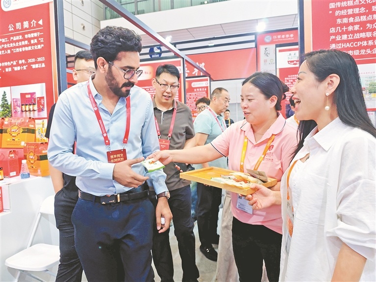 工作人员向参加2026第十届中华老字号（山东）博览会的外国友人推荐东南饼庄的产品。（资料图）