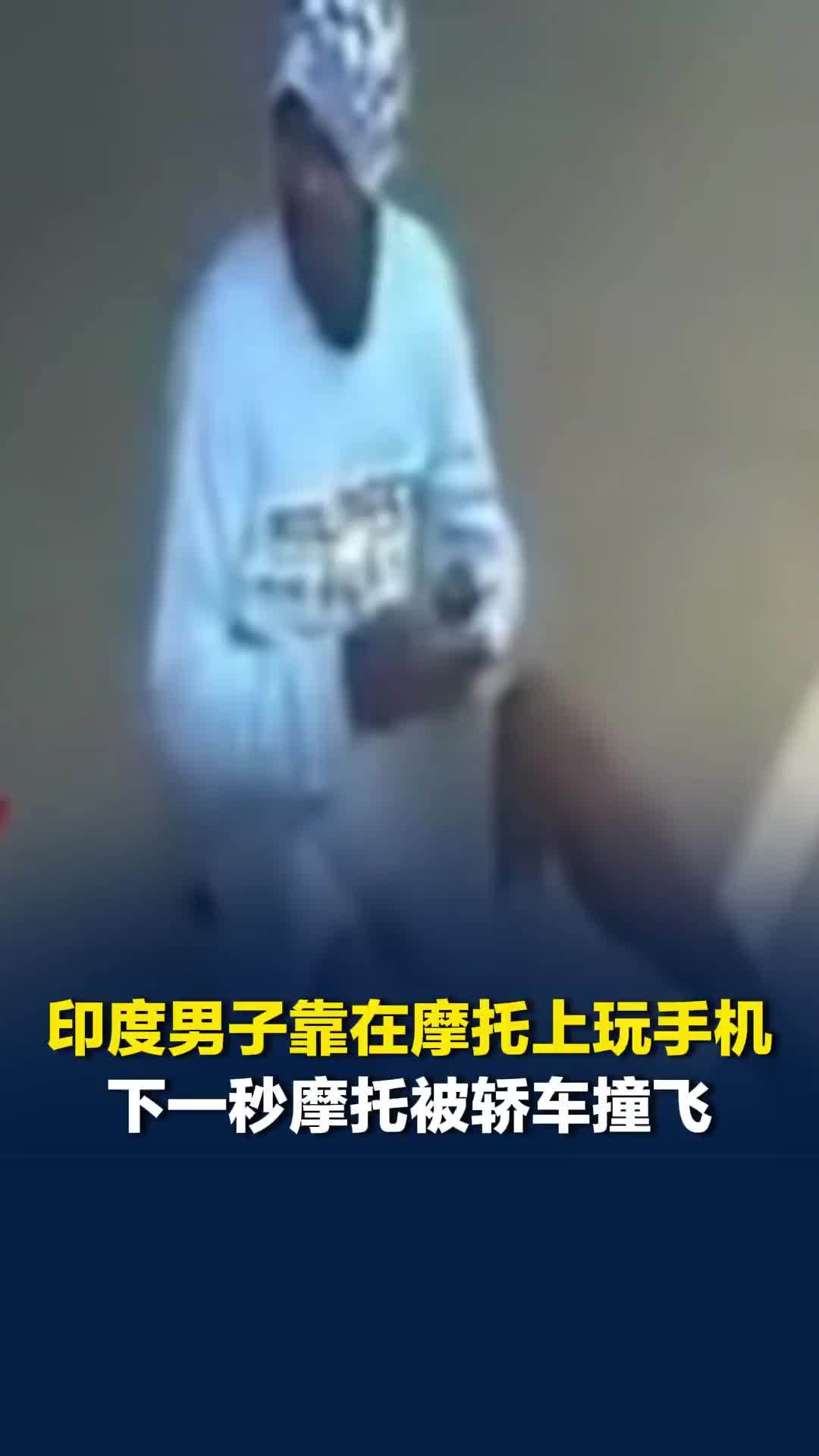 印度男子靠在摩托上玩手机，下一秒摩托被轿车撞飞，本人留在原地毫发无损