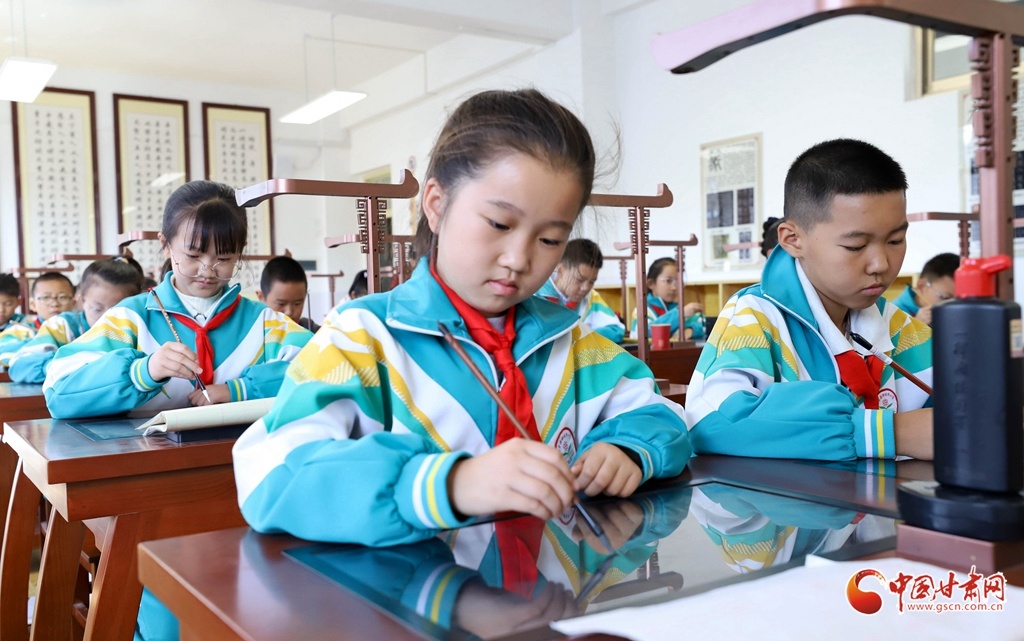 10月13日,张掖市高台县解放街小学智慧书法教室内,同学们在电子屏和投影的指引下进行书法练习。