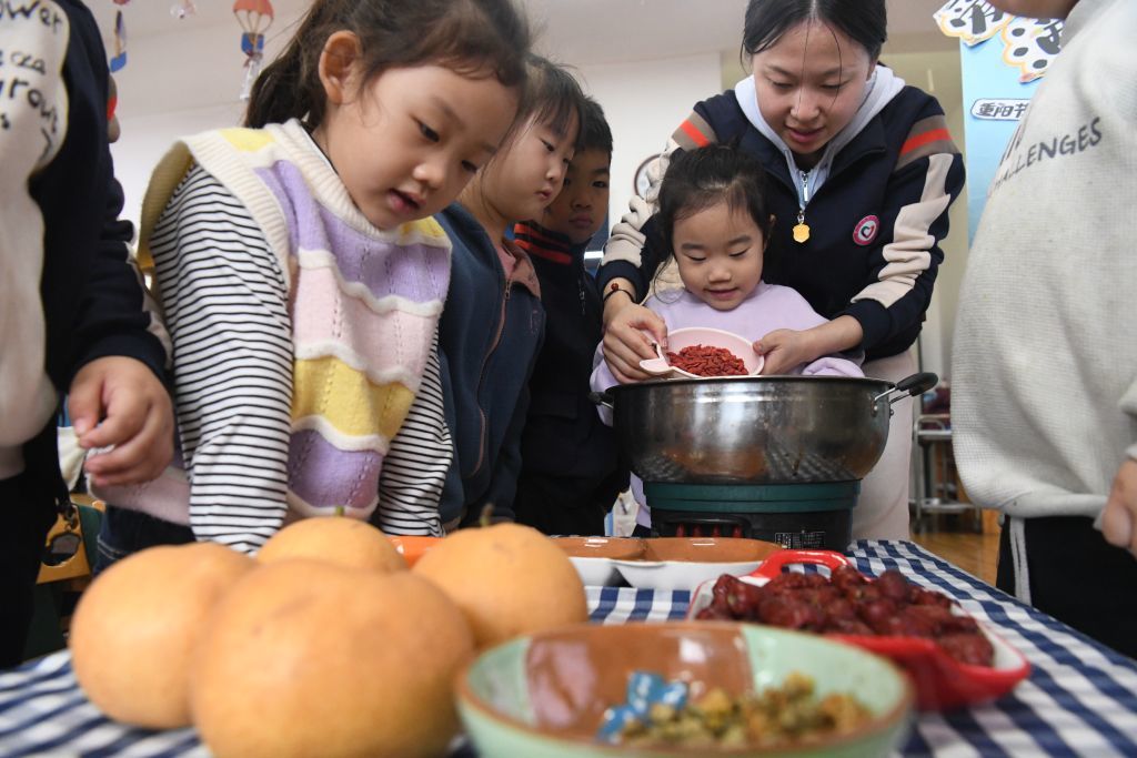 在河北省邯郸市广平县第四幼儿园,老师指导小朋友学习制作重阳菊花茶。新华社发(程学虎 摄)