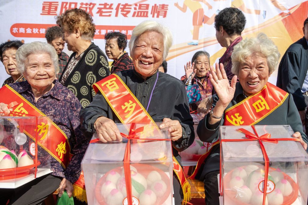 在浙江省温州市鹿城区万源社区,白发老人在迎重阳活动上手捧寿桃礼盒。新华社发(刘吉利 摄)