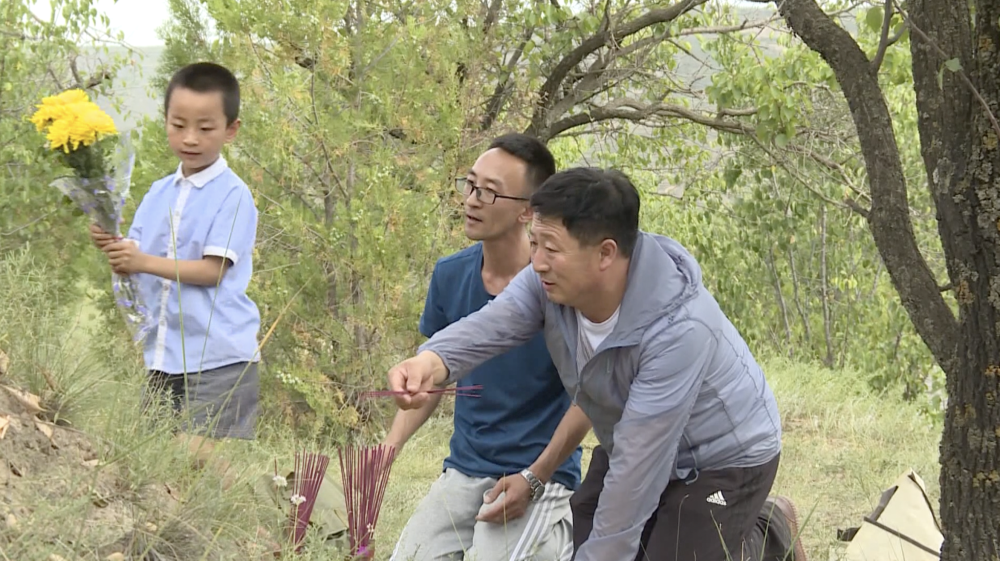 2016年，魏永强（中）和儿子还有叔叔魏长征在家中祖坟旁祭奠小红军（受访者供图）。