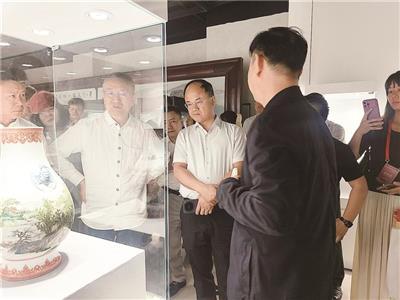 “瓷脉薪传”现当代陶瓷艺术精品展现场，参观者观看精美陶瓷。
