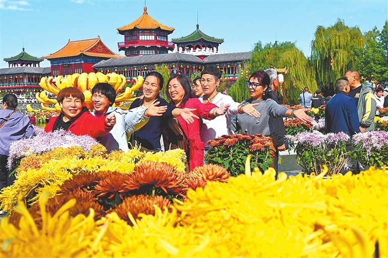 10月18日,游客在中国翰园碑林内观赏菊花并拍照留念。 李俊生 摄