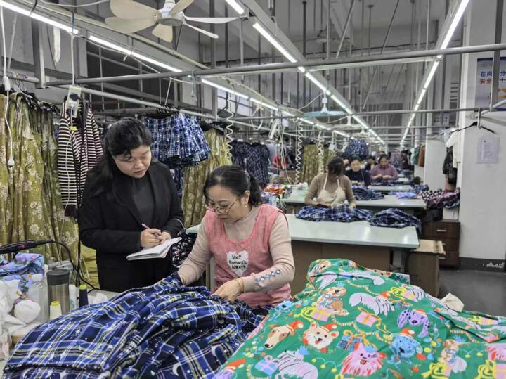 采访团记者和制衣厂工人交谈