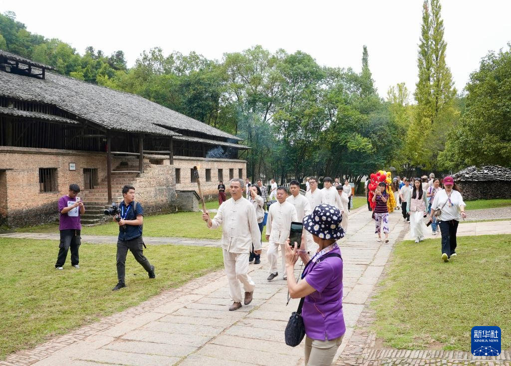 10月19日，点火仪式前，古窑民俗博览区的工作人员在景区内传递复烧馒头窑的火种。新华社记者 胡晨欢摄