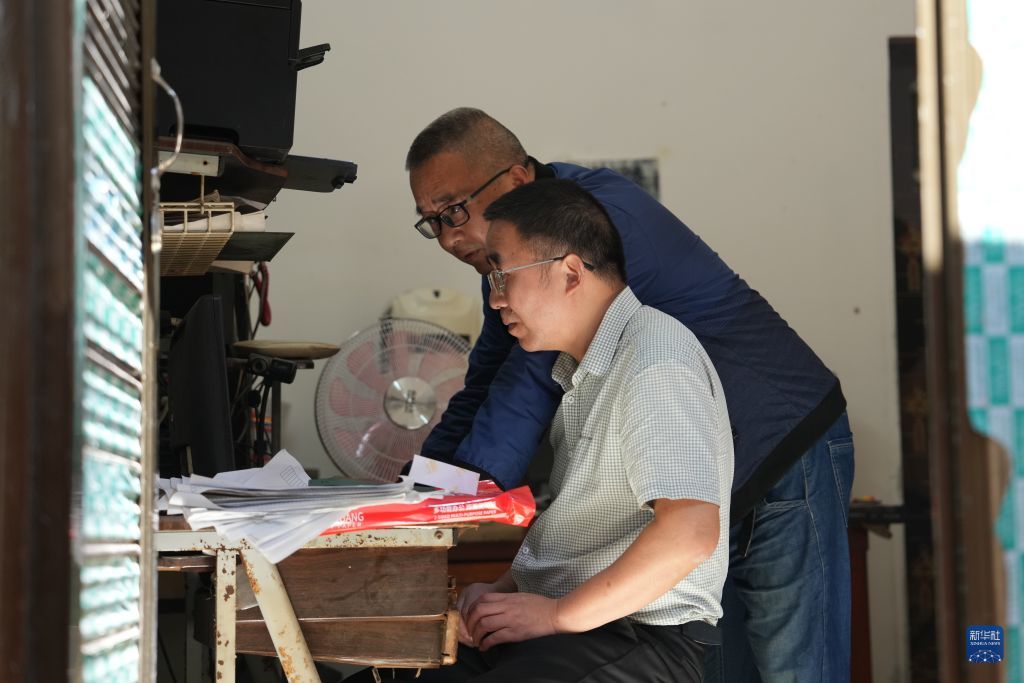 2026年10月10日,胡文胜与胡文杰(前)在水月楼照相馆内用电脑处理照片。
