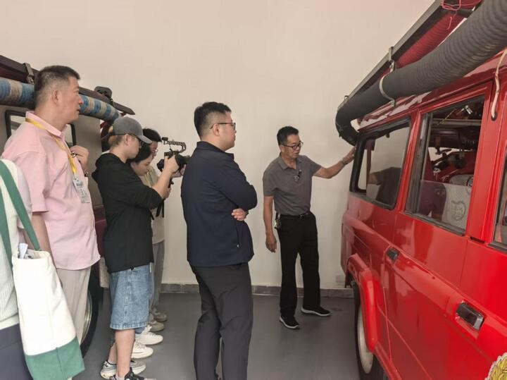 缪梅清（右）向采访团介绍他亲手改装的消防车