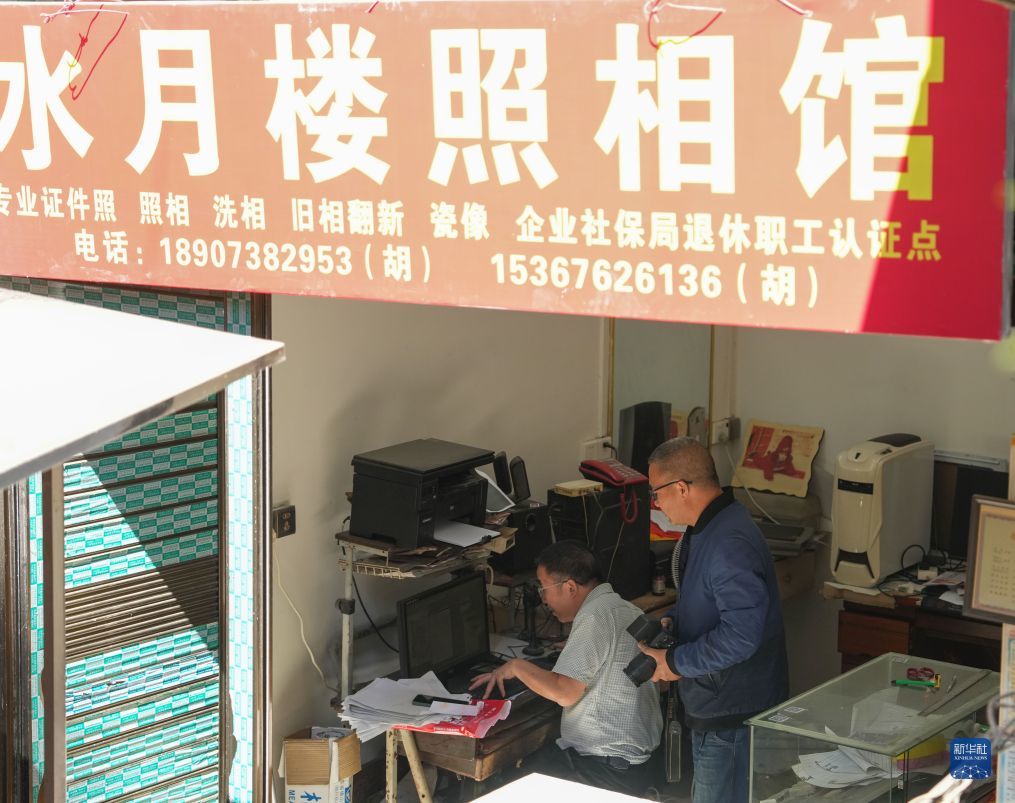 2026年10月10日,胡文胜(右)与弟弟胡文杰(左)在水月楼照相馆内用电脑处理照片。