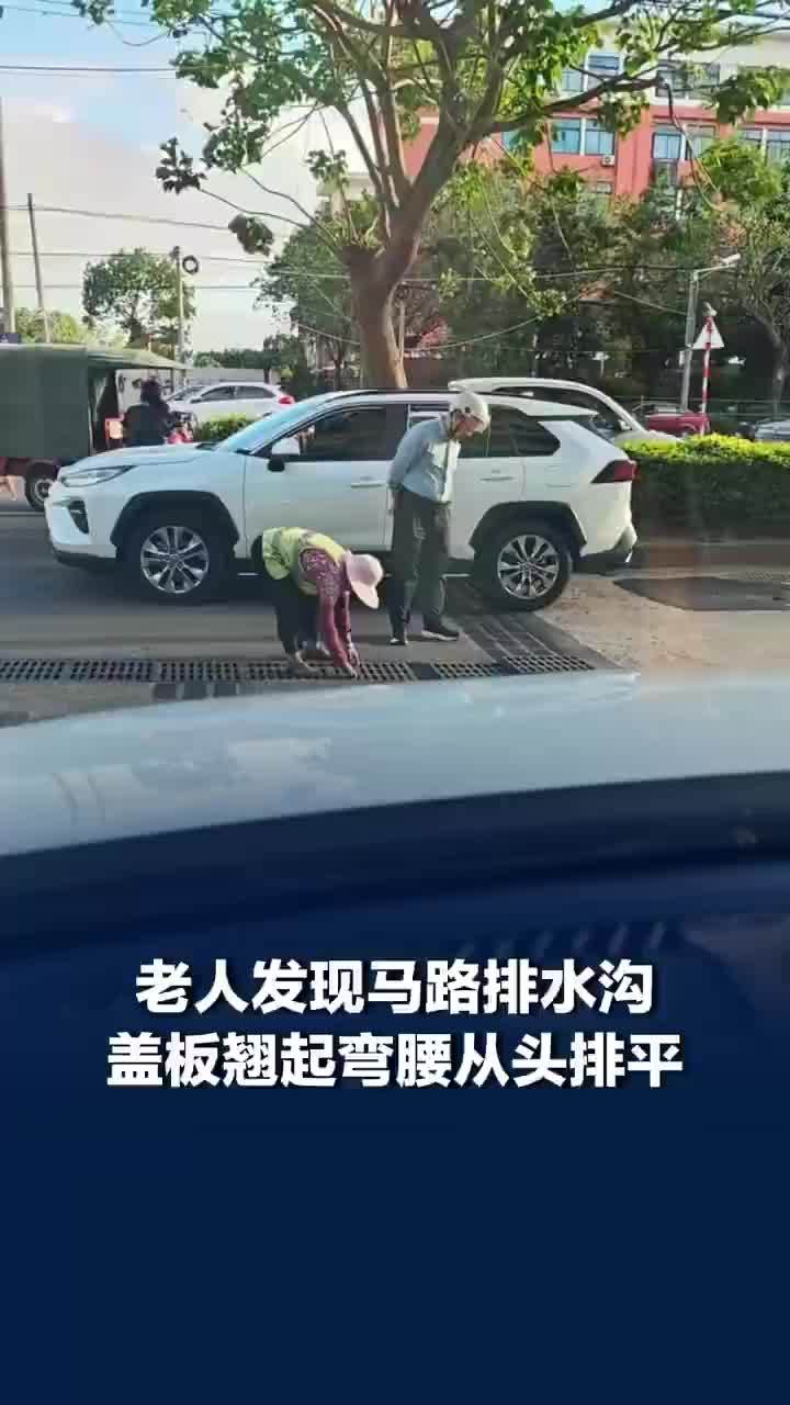 马路排水沟盖板翘起老人弯腰帮排平