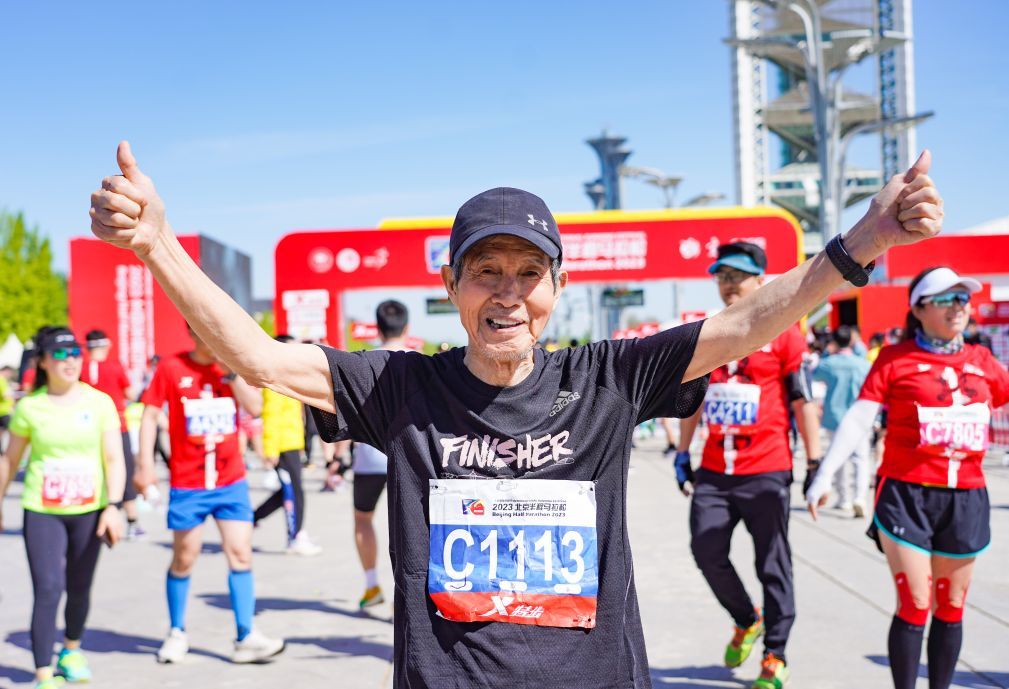 2023年4月16日，一名老年马拉松爱好者在2023北京半程马拉松比赛终点区域庆祝完赛。新华社记者　陈钟昊　摄