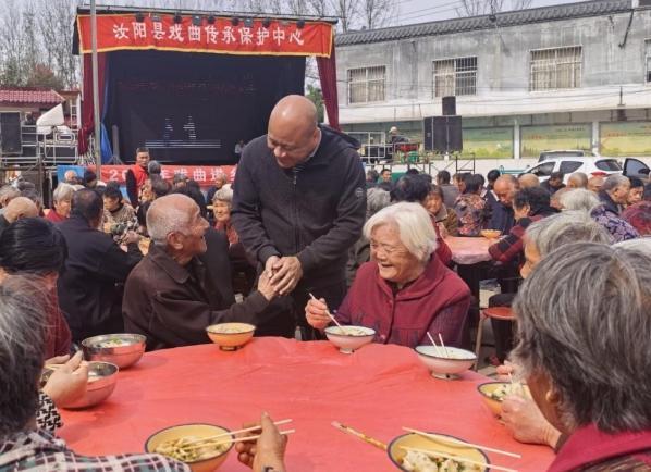 老人们吃着饺子看着戏，拉着工行驻村第一书记的手聊家常