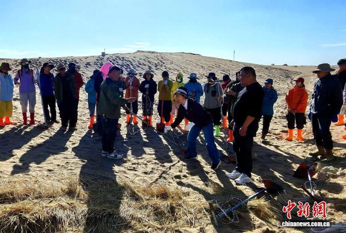民勤林业工程师现场示范规范压沙操作，指导志愿者科学布设草方格。荣小勤　摄