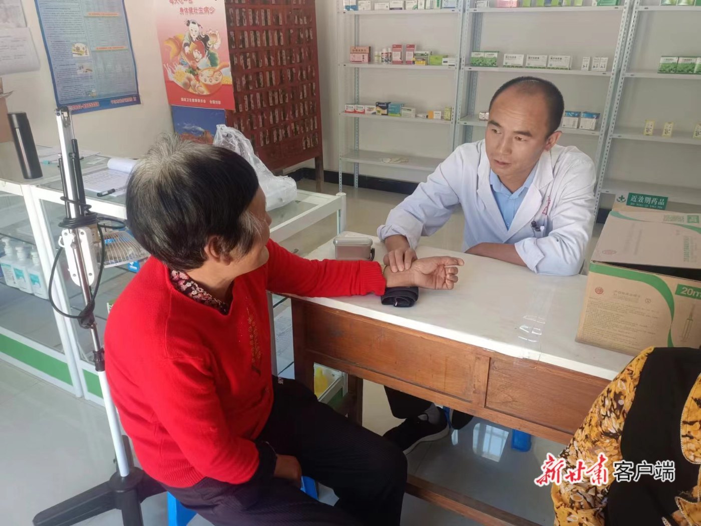 灵台县龙门乡卫生院院长杨安福（右四）为患者问诊把脉