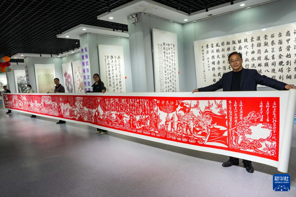 10月17日,在会宁县文化馆,王新胜与大家一起展示自己创作的15米剪纸长卷《长征》。新华社记者 郎兵兵 摄