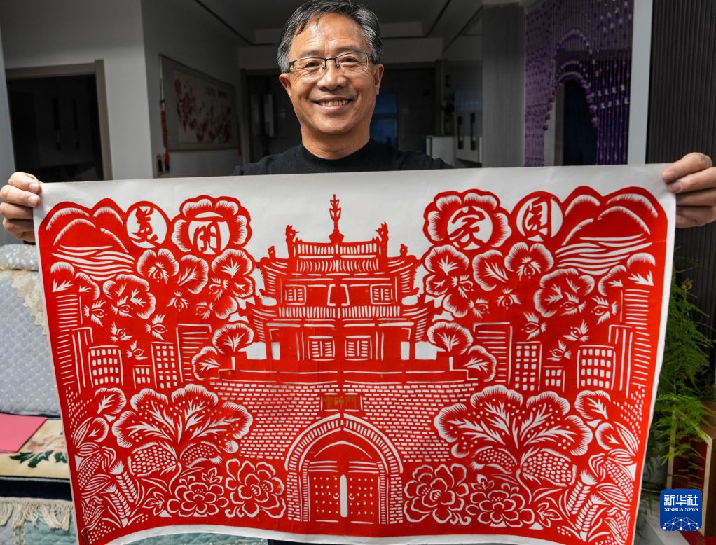 10月16日,王新胜展示自己创作的会师门剪纸作品。新华社记者 郎兵兵 摄