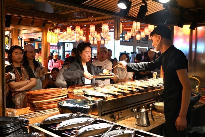 游客在敦煌夜市沙州食驿选购美食 新华社发(张晓亮 摄)