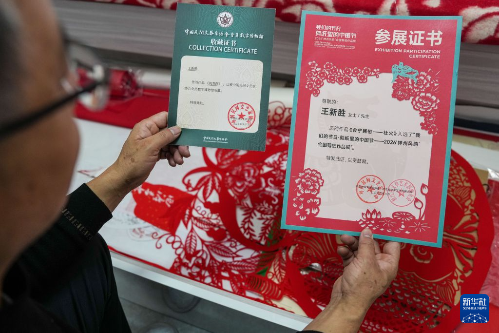 10月17日,王新胜展示自己的作品被中国民间文艺家协会收藏的证书。新华社记者 郎兵兵 摄
