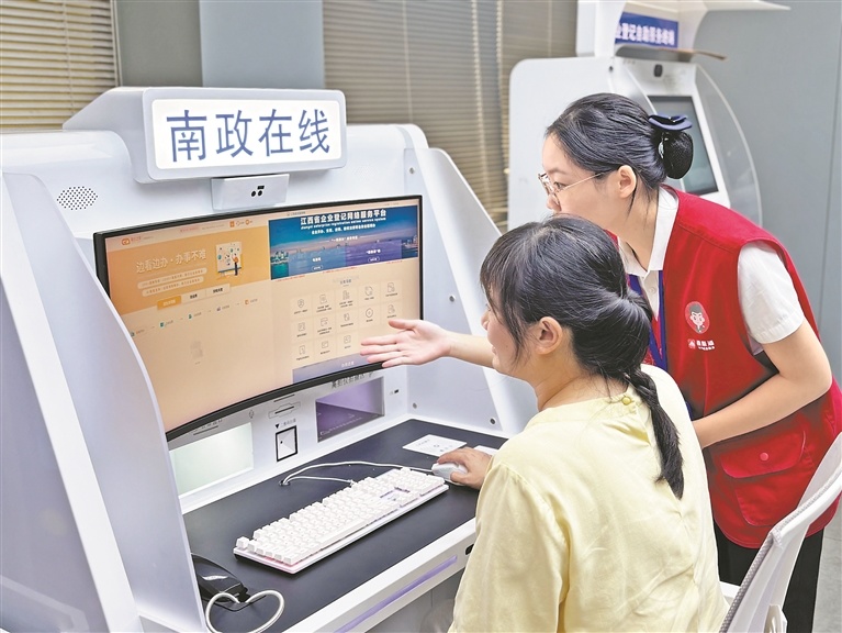 南昌县政务服务大厅内，工作人员指导群众操作“南政在线”智能自助终端。