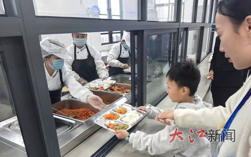 食堂阿姨给学生打菜。