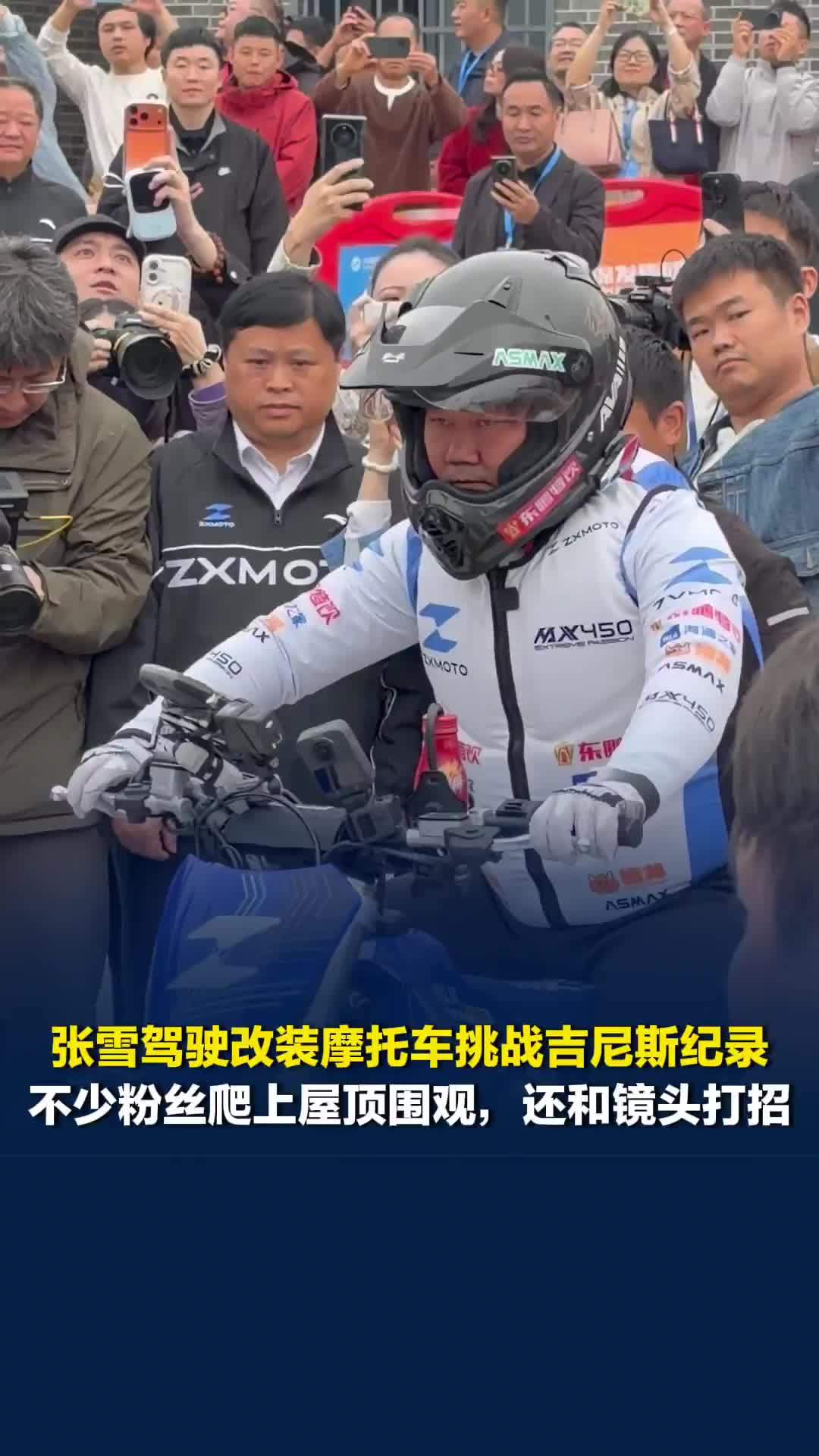 张雪驾驶改装摩托车挑战吉尼斯纪录，不少粉丝爬上屋顶围观，还和镜头打招